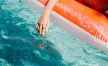 woman dangles her hand in the pool as she floats in an inflatable vessel